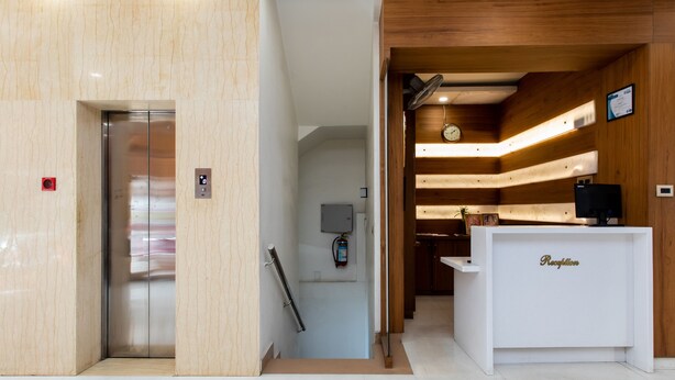 A reception area with a reception desk, a clock, and a fire extinguisher. - Capital O 27658 Hotel New Mohit Regency (Bhopal)