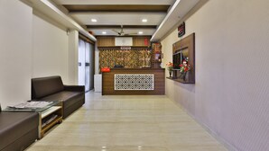 A reception area with a reception desk, a sofa, and a ceiling fan. - Hotel Tirupati - Ahmedabad (Ahmedabad)