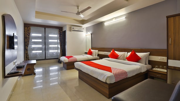 A hotel room with two beds, a TV, a desk, and a wardrobe. - Hotel Tirupati - Ahmedabad (Ahmedabad)