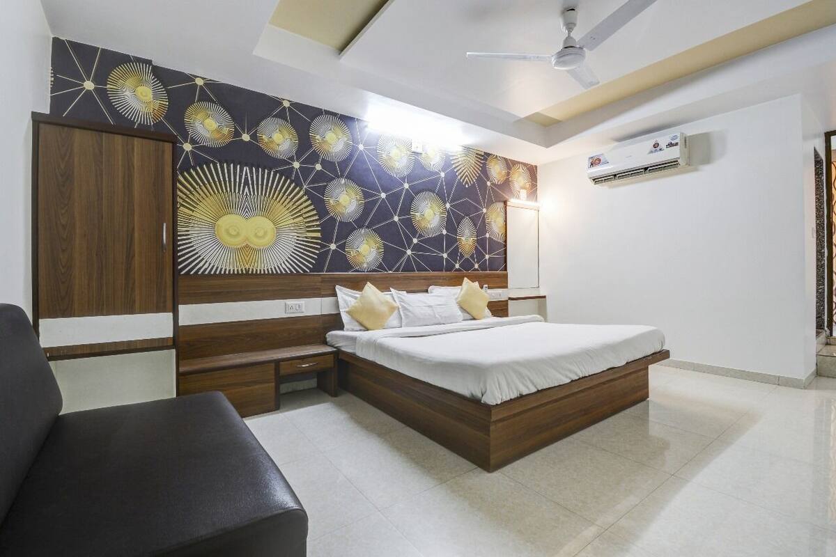 A modern bedroom with a large bed, a wooden wardrobe, a desk, and a chair.