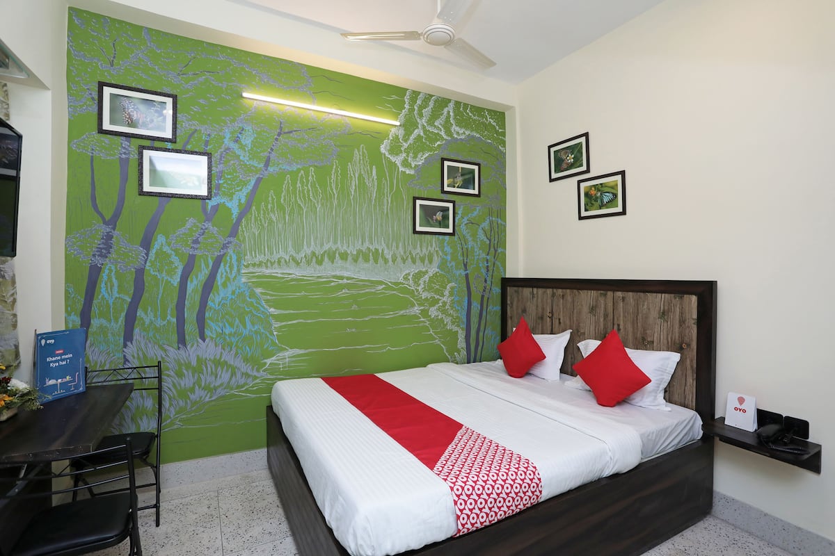 A hotel room with a bed, a desk, and a green wall mural.