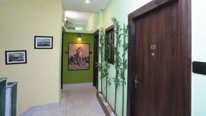 Un pasillo con paredes verdes, una puerta de madera y un cuadro enmarcado de un tigre.