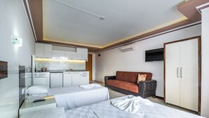 A hotel room with a bed, a sofa, a TV, a wardrobe, and a kitchenette. - Ustun Apart Hotel (Alanya)
