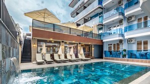 A hotel with a swimming pool, outdoor seating, and a covered area with umbrellas. - Ustun Apart Hotel (Alanya)