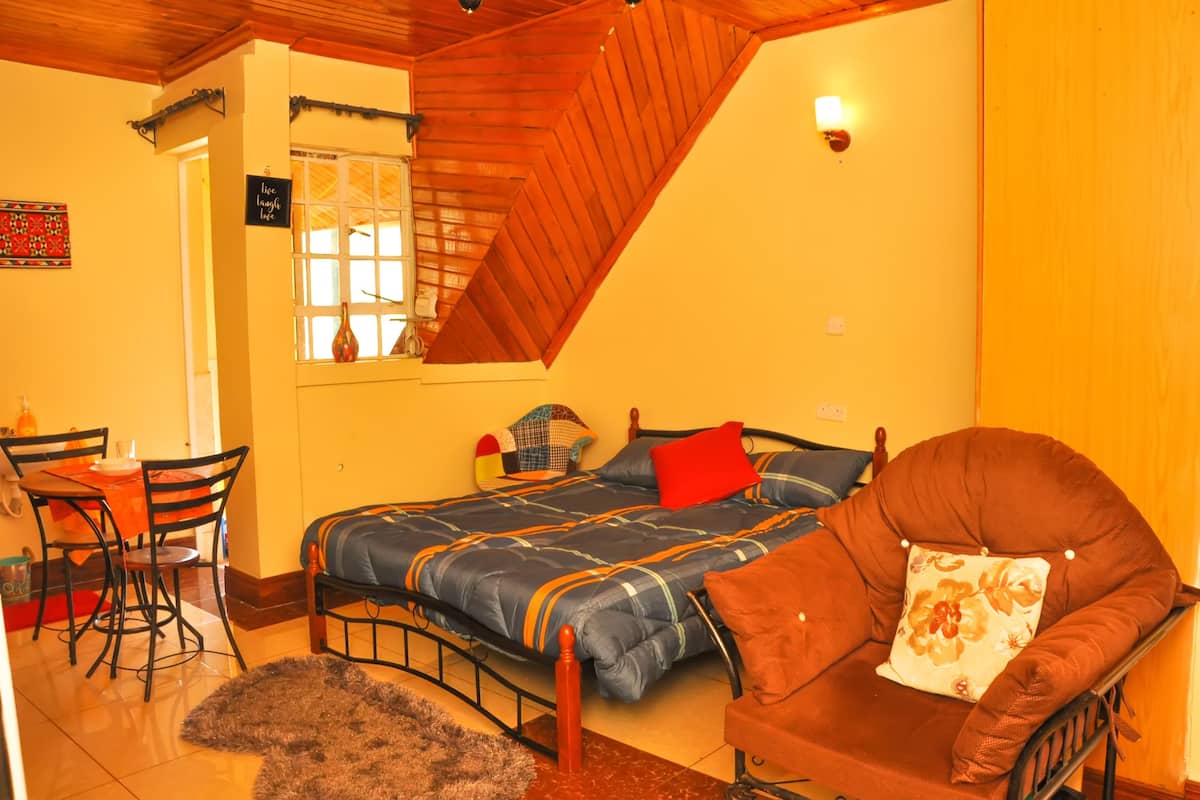 A cozy bedroom with a bed, a chair, a small table, and a window.