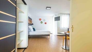 A compact room with a bed, a desk, and a shelf unit.