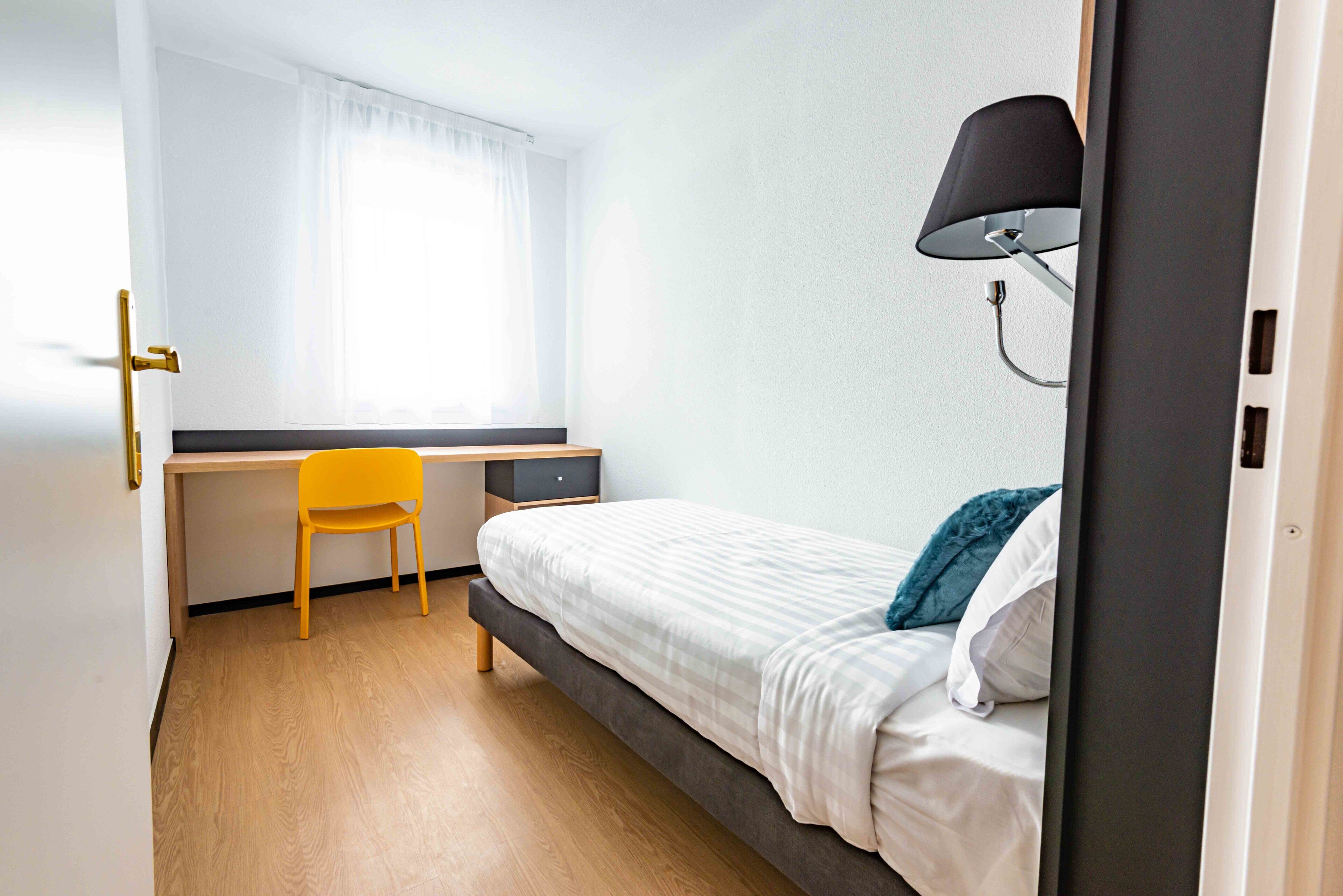Una habitación con una cama, un escritorio y una silla.