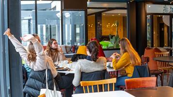 A group of people seated around a table in a modern cafe with large windows and a view of the cityscape.