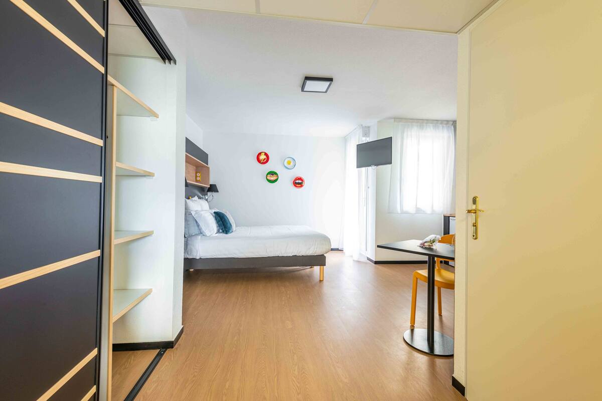 Een kleine kamer met een bed, bureau en kledingkast.