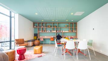 A modern library with a teal ceiling, wooden bookshelves, and a variety of seating options.