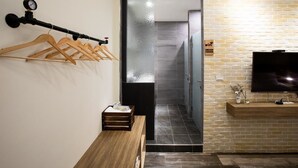 Habitación de hotel con un banco de madera, un televisor fijado a la pared y un perchero.