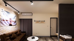 Un salón moderno con pared de ladrillo, un sofá marrón, una mesa blanca y una puerta con perchero.