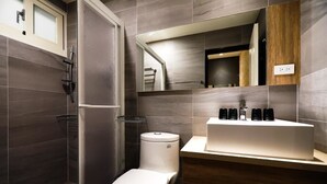 Un baño moderno con inodoro, lavabo, espejo y zona de ducha.
