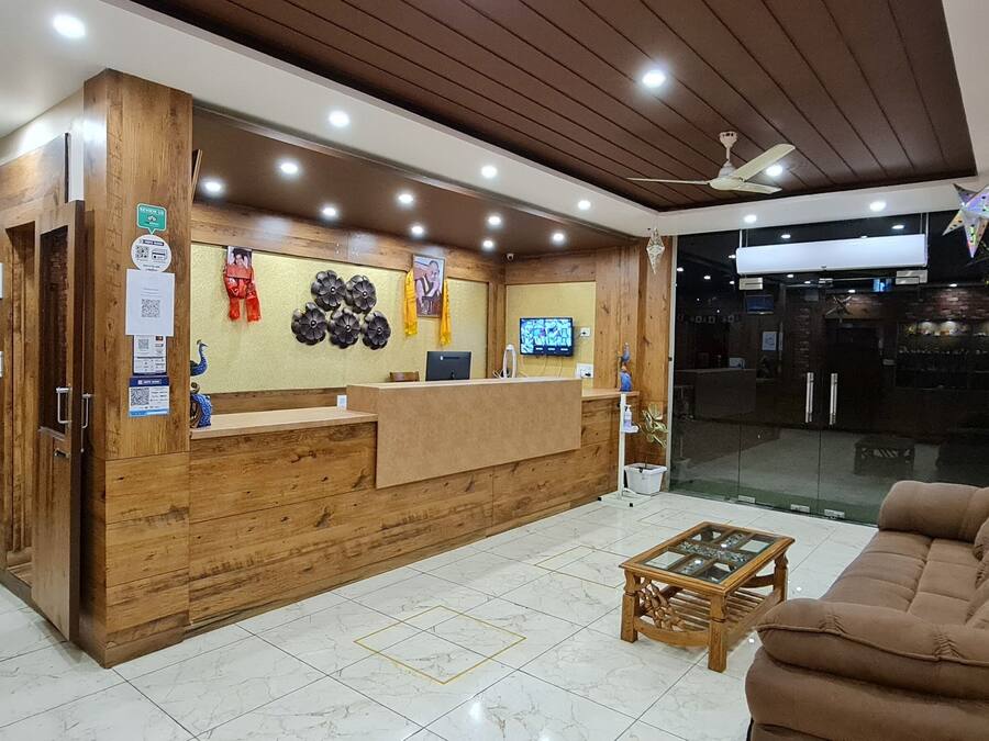 Un espace d’accueil comprenant un comptoir de réception en bois, un canapé marron et une petite table.