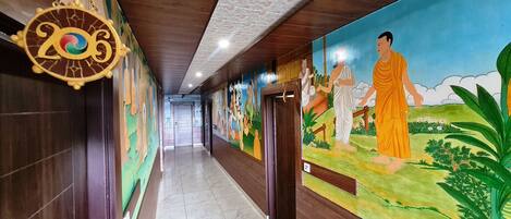 A hallway with a mural of a monk, a Buddha statue, and a decorative sign with the number 2023.