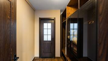 Un pasillo con una puerta de madera, un armario de madera y un closet con espejo.