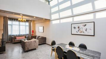 A spacious living area with a dining table, sofas, and a chandelier.