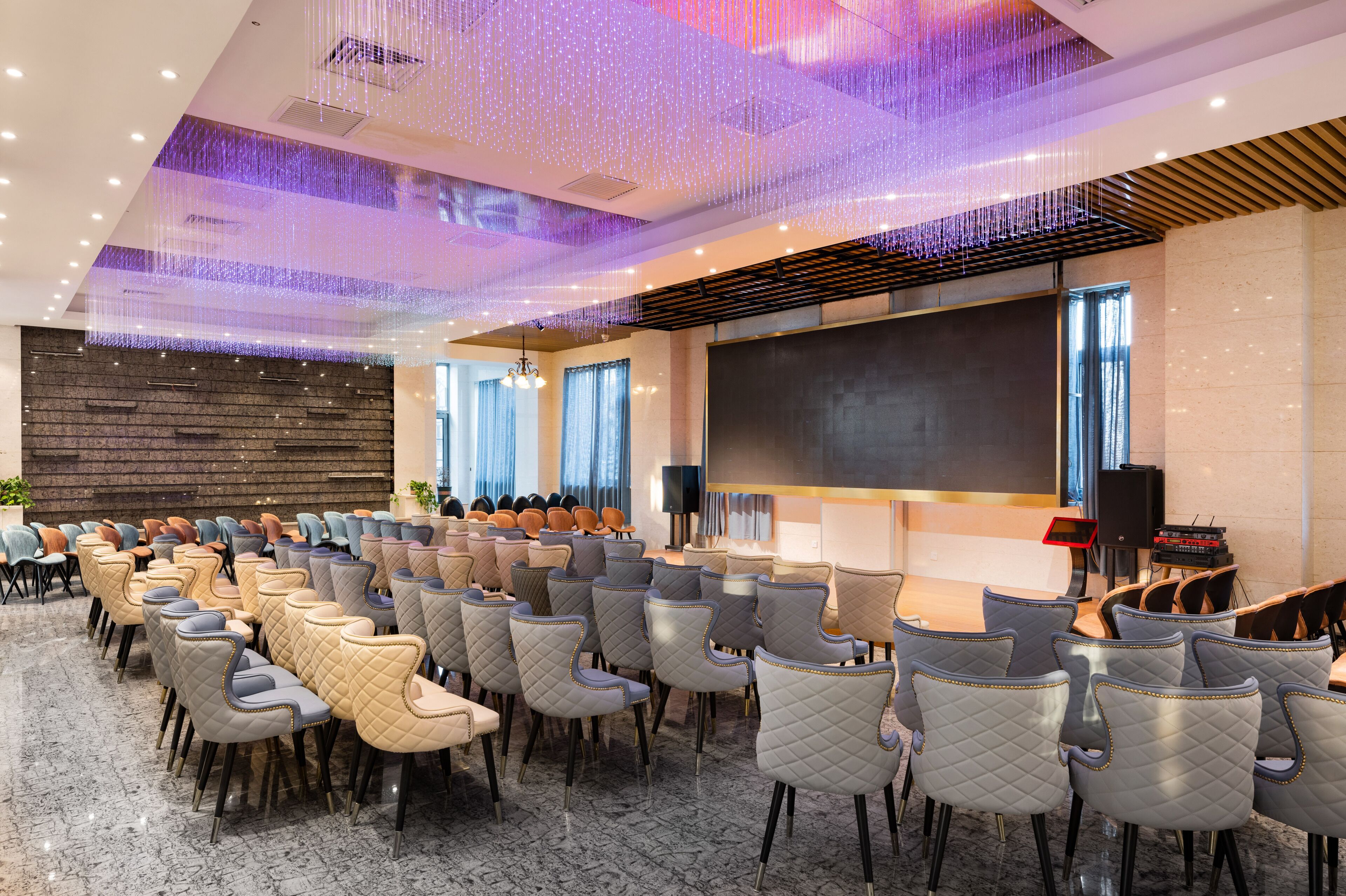 A conference room with rows of chairs, a large screen, and a modern ceiling design.