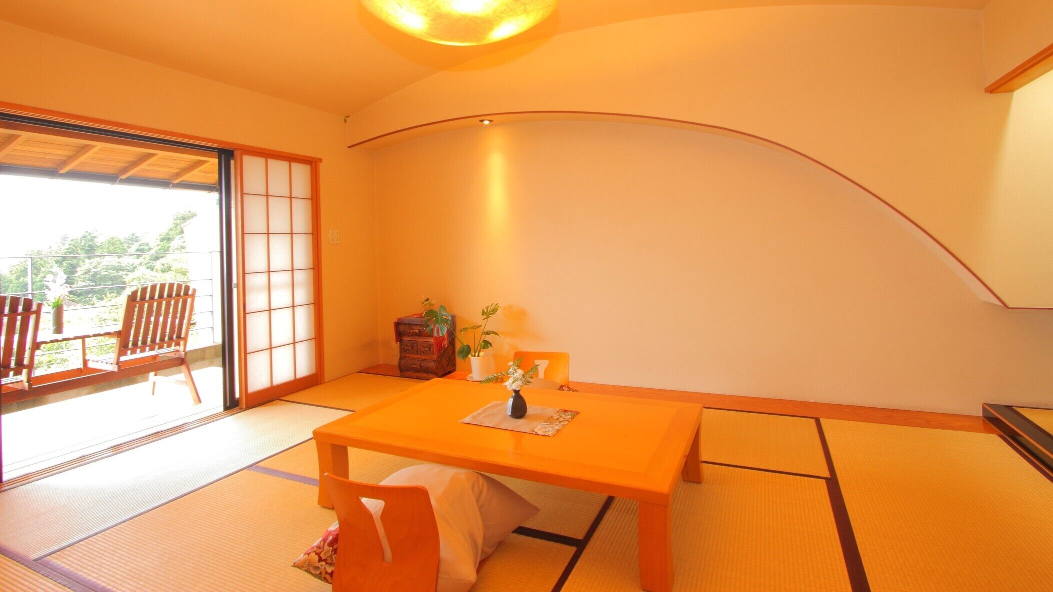 A room with tatami flooring, a low table, a chair, a small cabinet, and a sliding door leading to a balcony.