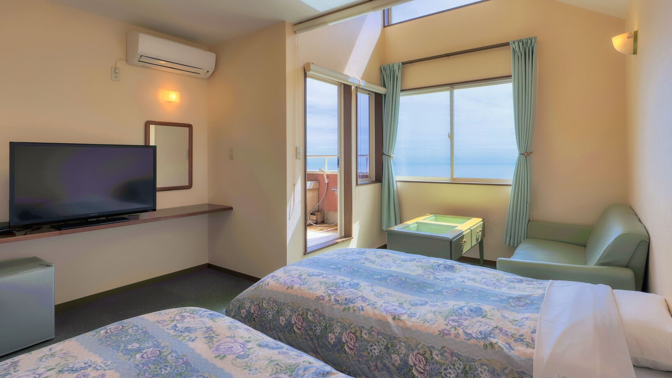 A hotel room with two beds, a television, a small table, and a window with curtains.