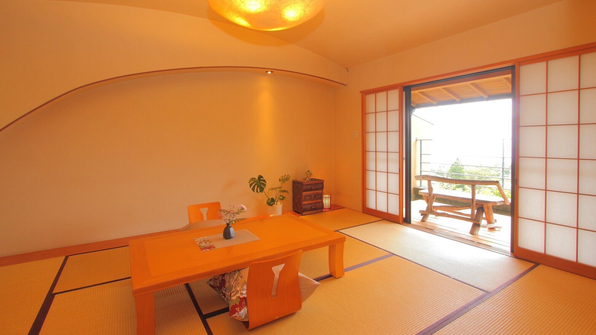 A traditional Japanese room with tatami flooring, a low table, a chair, a small cabinet, and a sliding door leading to an outdoor area.