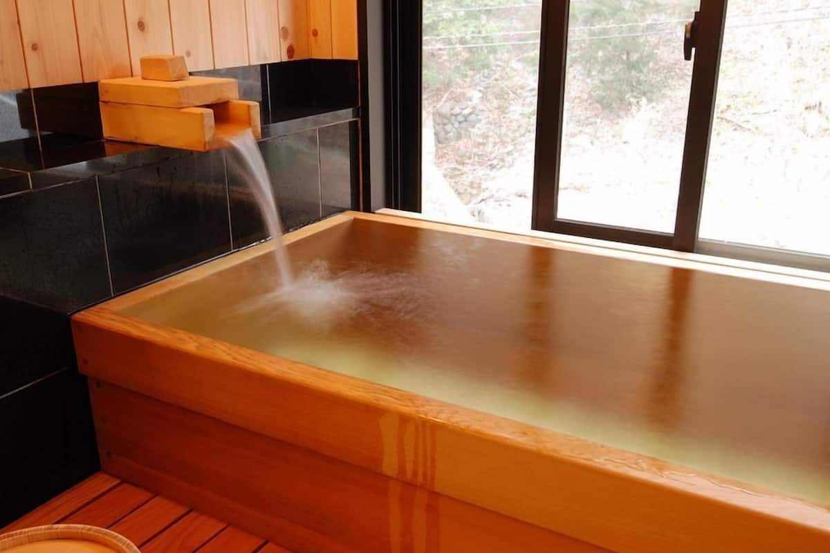 A wooden hot tub with a clear view of the outside through a window.