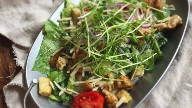 A metal serving dish with a salad on a wooden table. - Hotell Isbolaget (Donsö)