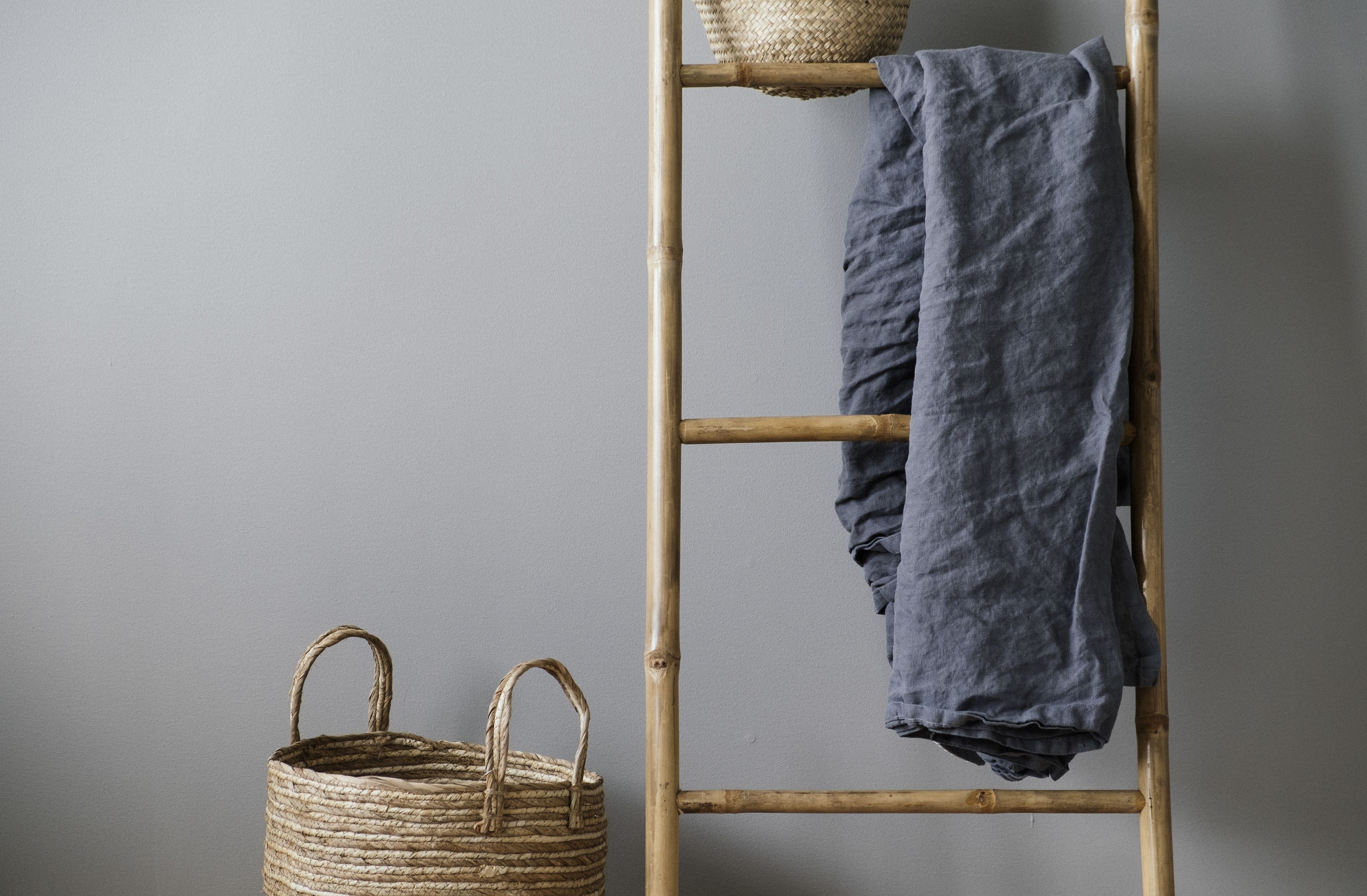 A bamboo ladder with a woven basket and a grey cloth.