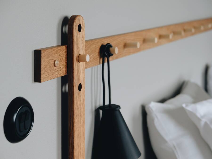 A wooden bed frame with a headboard, a black lamp, and a wall-mounted control panel.