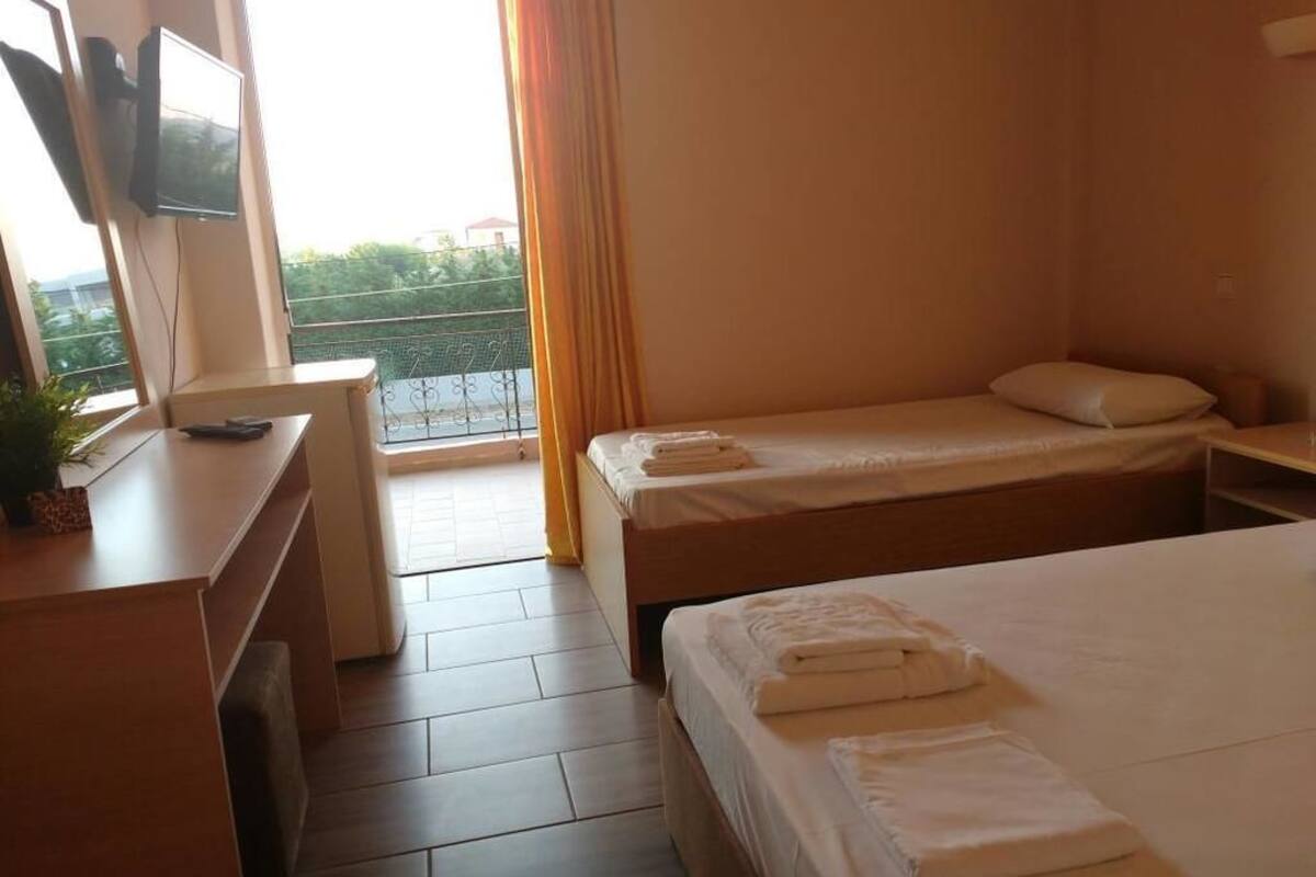 Een hotelkamer met een bed, een bureau met een televisie en een balkon met uitzicht.
