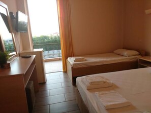 Una habitación de hotel con cama, escritorio y televisor, además de un balcón con vistas.
