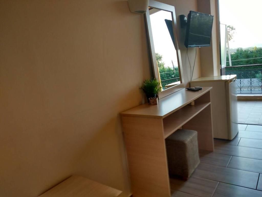 Una habitación moderna con un gran ventanal, un televisor de pantalla plana montado en la pared, una planta pequeña sobre una consola y un banco.