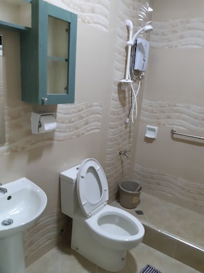 A bathroom with a toilet, sink, shower, and a cabinet with a mirror. - Zya Guest Home apartments (Baguio)