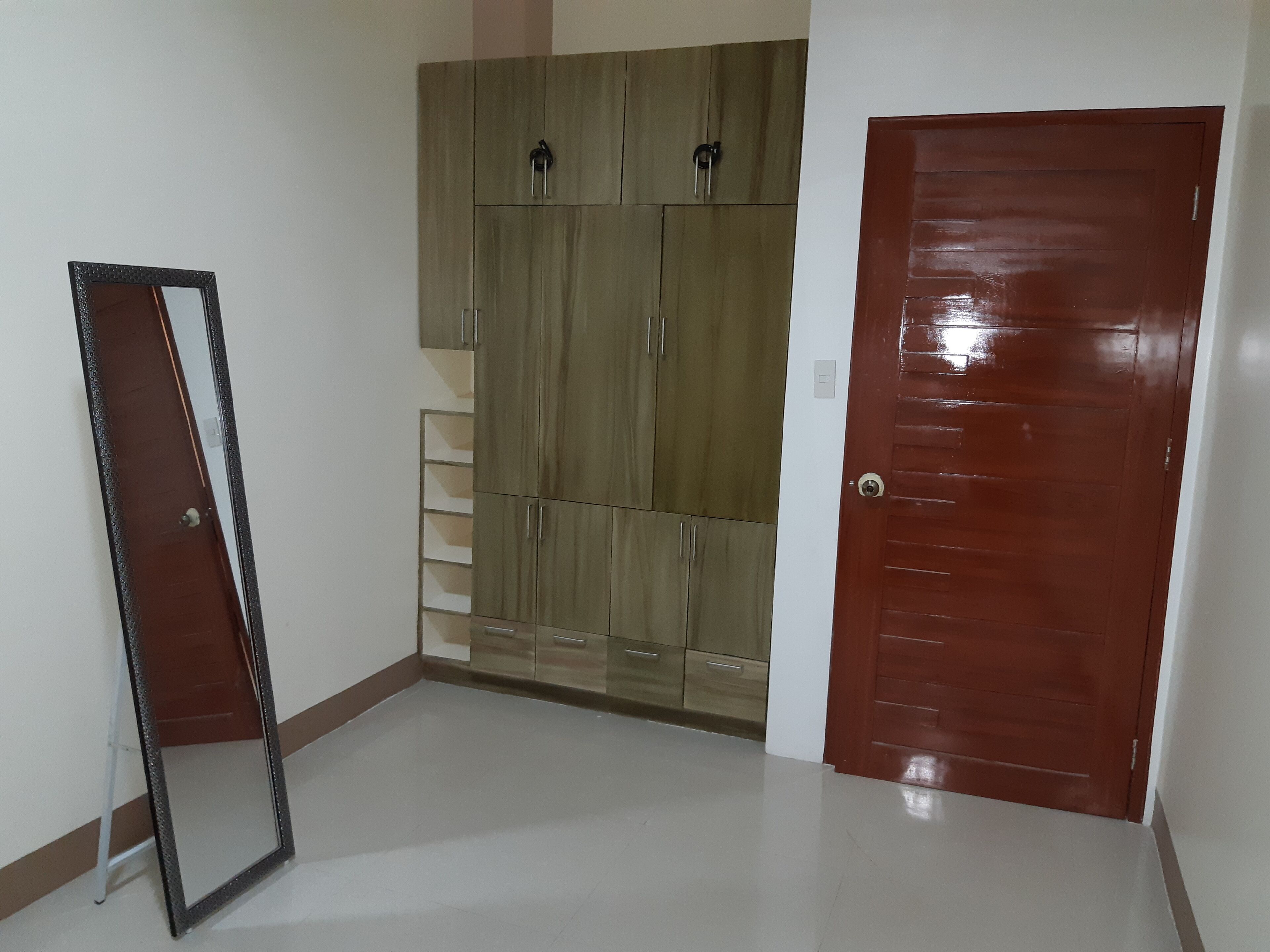 Une pièce avec une armoire, une porte et un miroir.