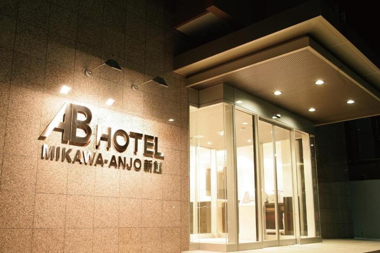 The exterior of a hotel with a prominent sign, a glass entrance, and a modern design.