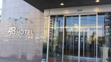 Esterno dell'hotel AB dal design moderno, con ampie porte in vetro e una bicicletta parcheggiata di fronte.