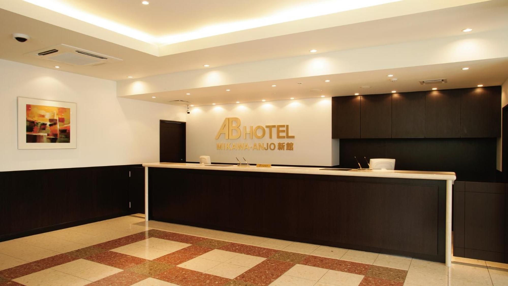 Zona de recepción de un hotel con diseño moderno, que incluye un mostrador de recepción, una obra de arte enmarcada en la pared y un cartel con el nombre del hotel.