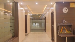 Un pasillo de hotel con puertas de vidrio, un mostrador de recepción de madera e iluminación empotrada en el techo.