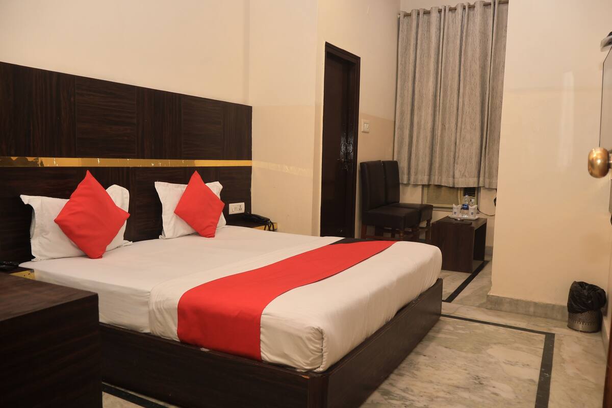 A hotel room with a bed, a desk, a chair, a TV, and a bathroom.