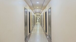Un pasillo largo y estrecho con puertas a ambos lados, iluminación empotrada y suelo brillante.