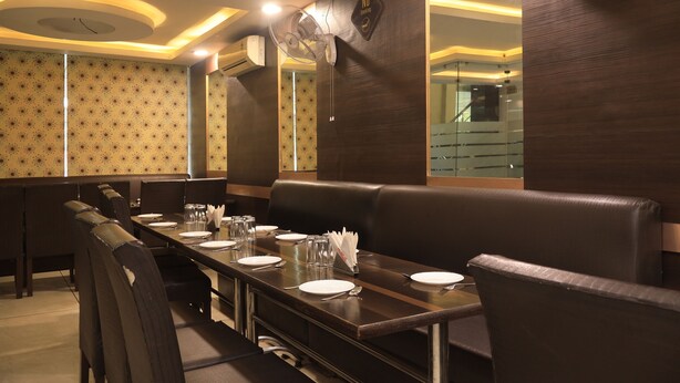 Un restaurante con una larga mesa de comedor, cabinas y una pared espejada.