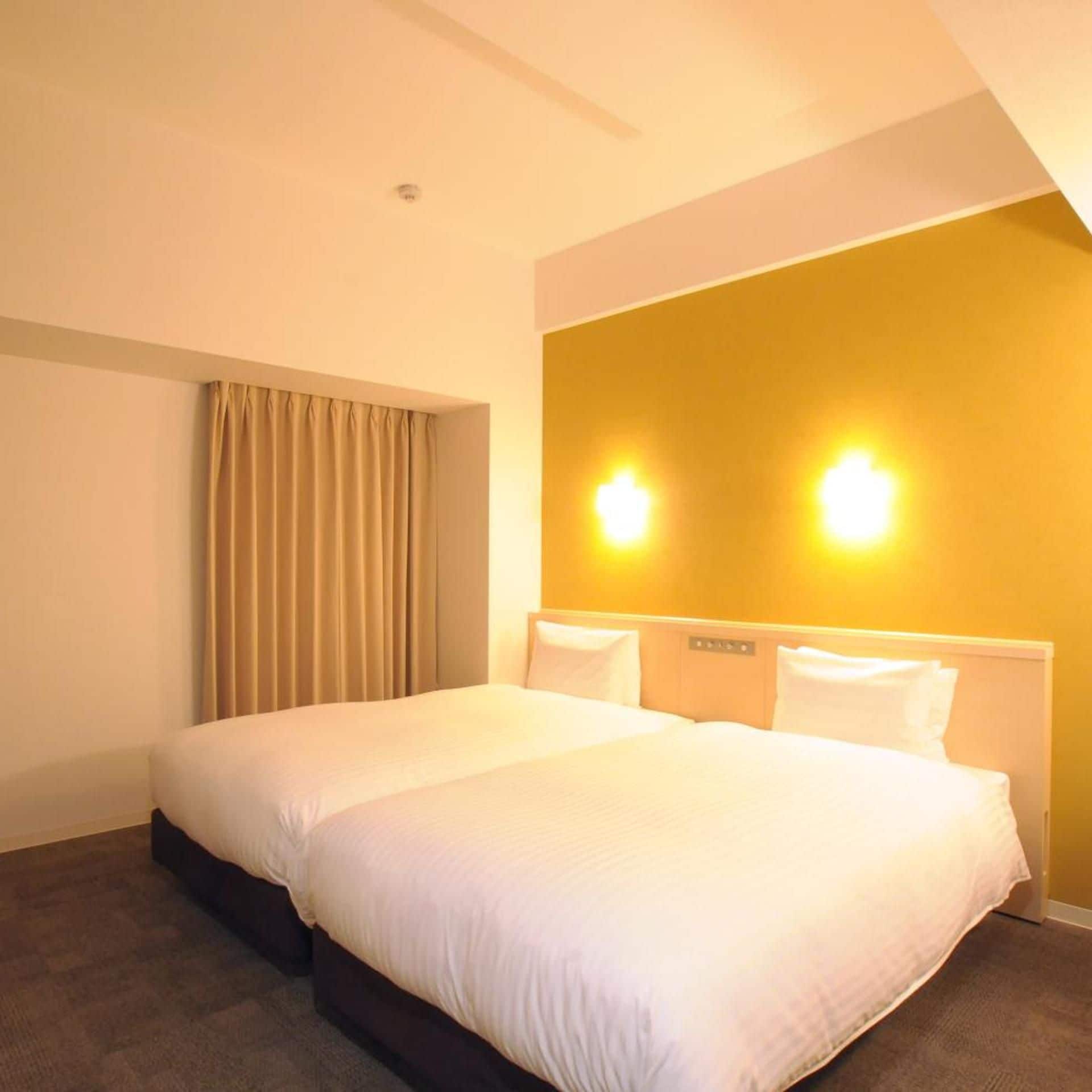 Een hotelkamer met een groot bed, een hoofdeinde met bedieningselementen, een gordijn en wandlampen.
