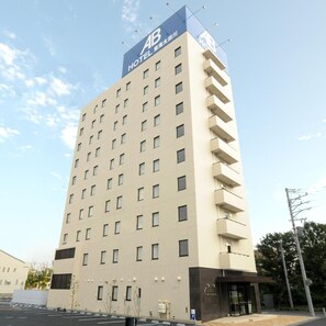 Een meerhoog hotelgebouw met een opvallend 'AB HOTEL' bord op de bovenkant.