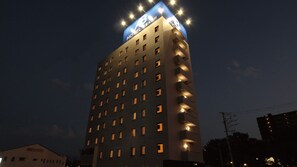 Un edificio de hotel alto con varios pisos, ventanas iluminadas y un letrero llamativo en la parte superior.