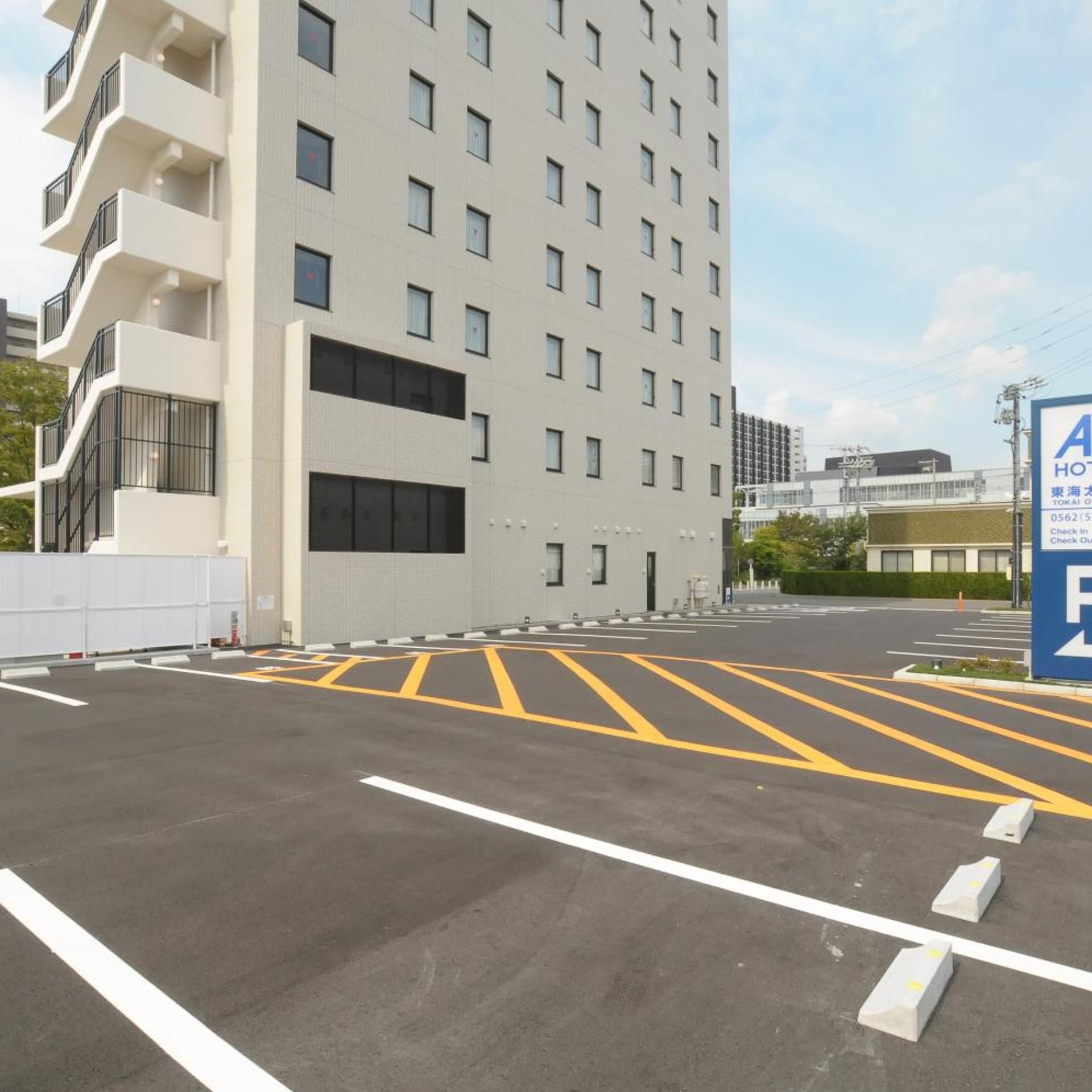 A hotel parking lot with marked spaces and a building with multiple floors and balconies.