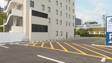 A hotel parking lot with marked spaces and a building with multiple floors and balconies.