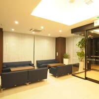 Uma área de espera moderna com sof ás, uma mesa e um painel de vidro.