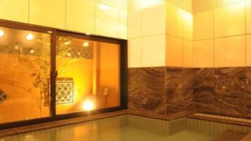 A spa area with a glass-enclosed room, a marble wall, and a tiled floor.