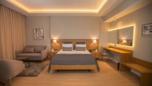 A modern hotel room with a large bed, bedside tables, a desk, a chair, and a sofa. - Gumushan Hotel (Korkuteli)