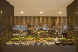 Monipuolinen buffet, jossa on tarjolla erilaisia ruokia ja ruokailuvälineitä.